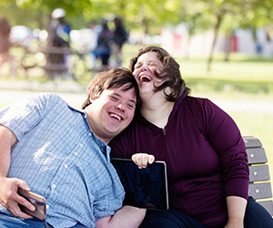 two people laughing on a park bench
