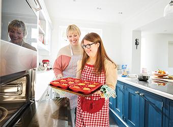 Client and support worker smiling while baking muffins together