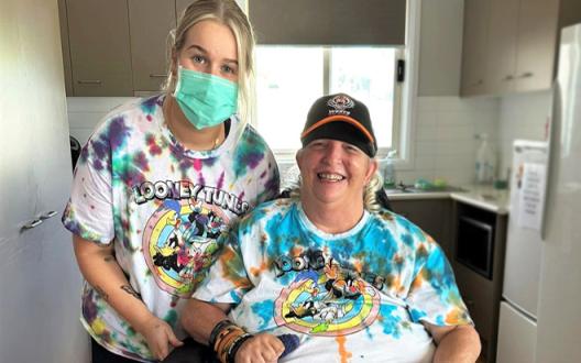 Supported independent living (SIL) client Col, with Unisson support worker (DSP) Emily, wearing their matching tie-dyed shirts.