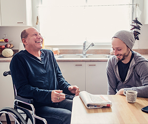 support worker and client laughing at dining table