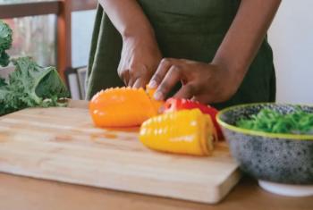 A person chopping vegetables in a kitchen