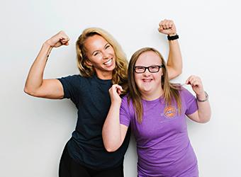 client and carer holding up arms showing off muscles while laughing