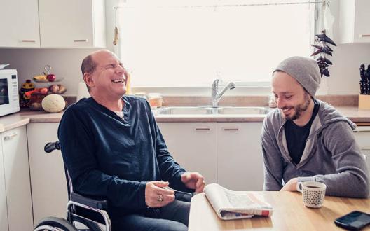 client and support worker laughing together at coffee table