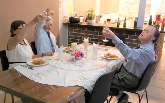 clients and support workers sitting around the dinner table hosting a dinner party 